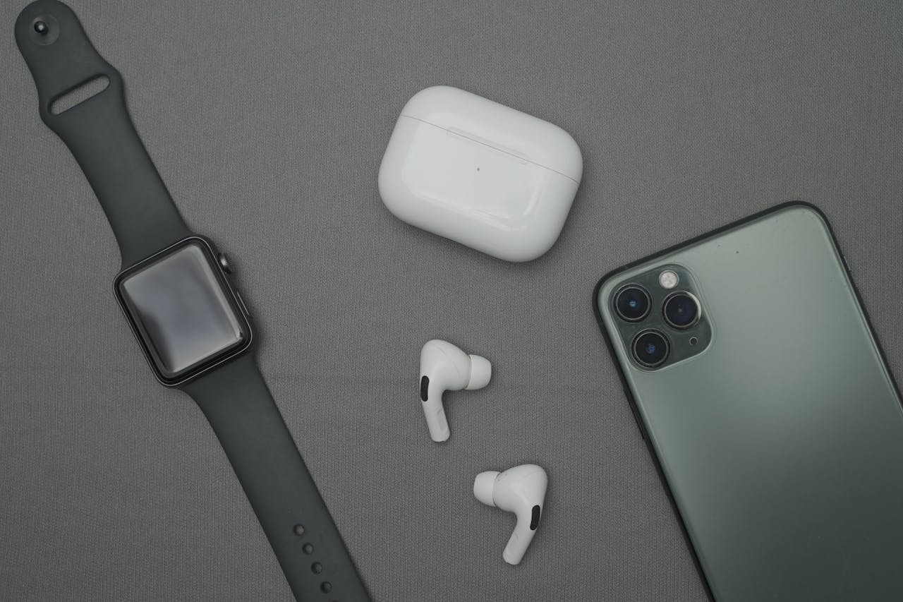 Home Flat lay of smartwatch, smartphone, and wireless earbuds on a gray background.